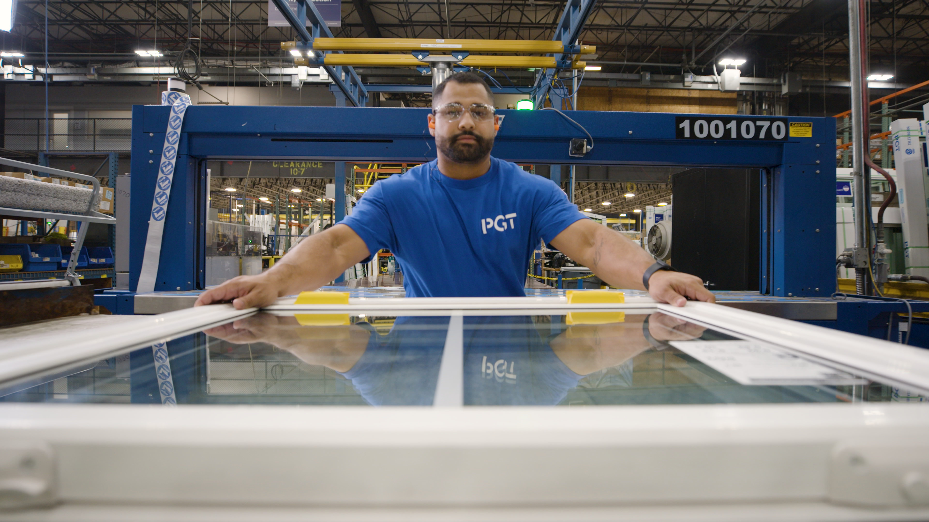 Man in a blue PGT shirt moving a window on the manufacturing line.