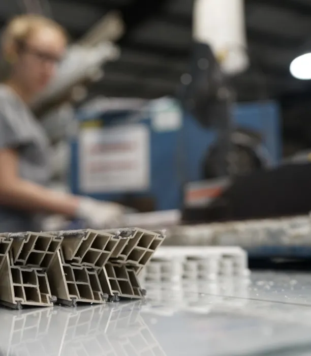 A close up of cut pieces of extruded vinyl with a woman working in the background.