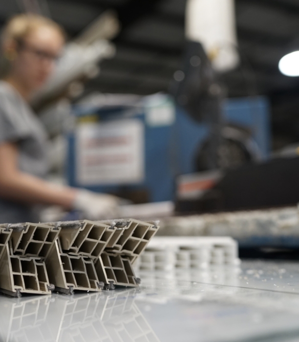 A close up of cut pieces of extruded vinyl with a woman working in the background.