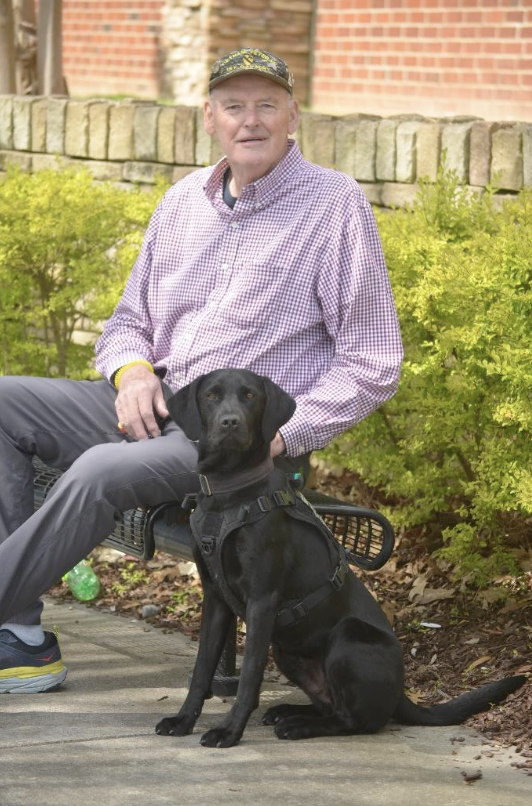 Vietnam veteran, Jim, sits with his black labrador retriever Ryder.